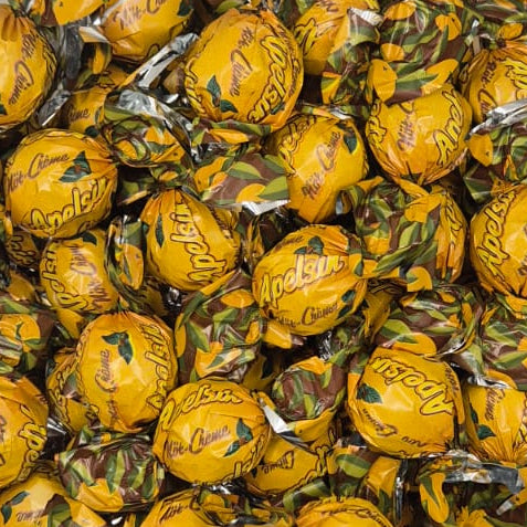 A clear plastic container filled with individually wrapped yellow chocolates on a plain white surface.
