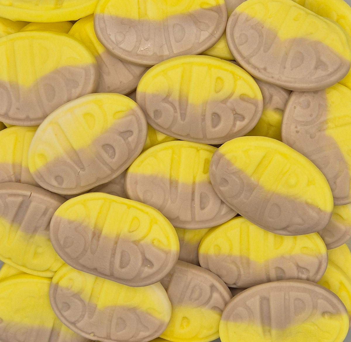 A close-up pile of oval candies with a two-tone yellow and light brown color scheme and embossed lettering.
