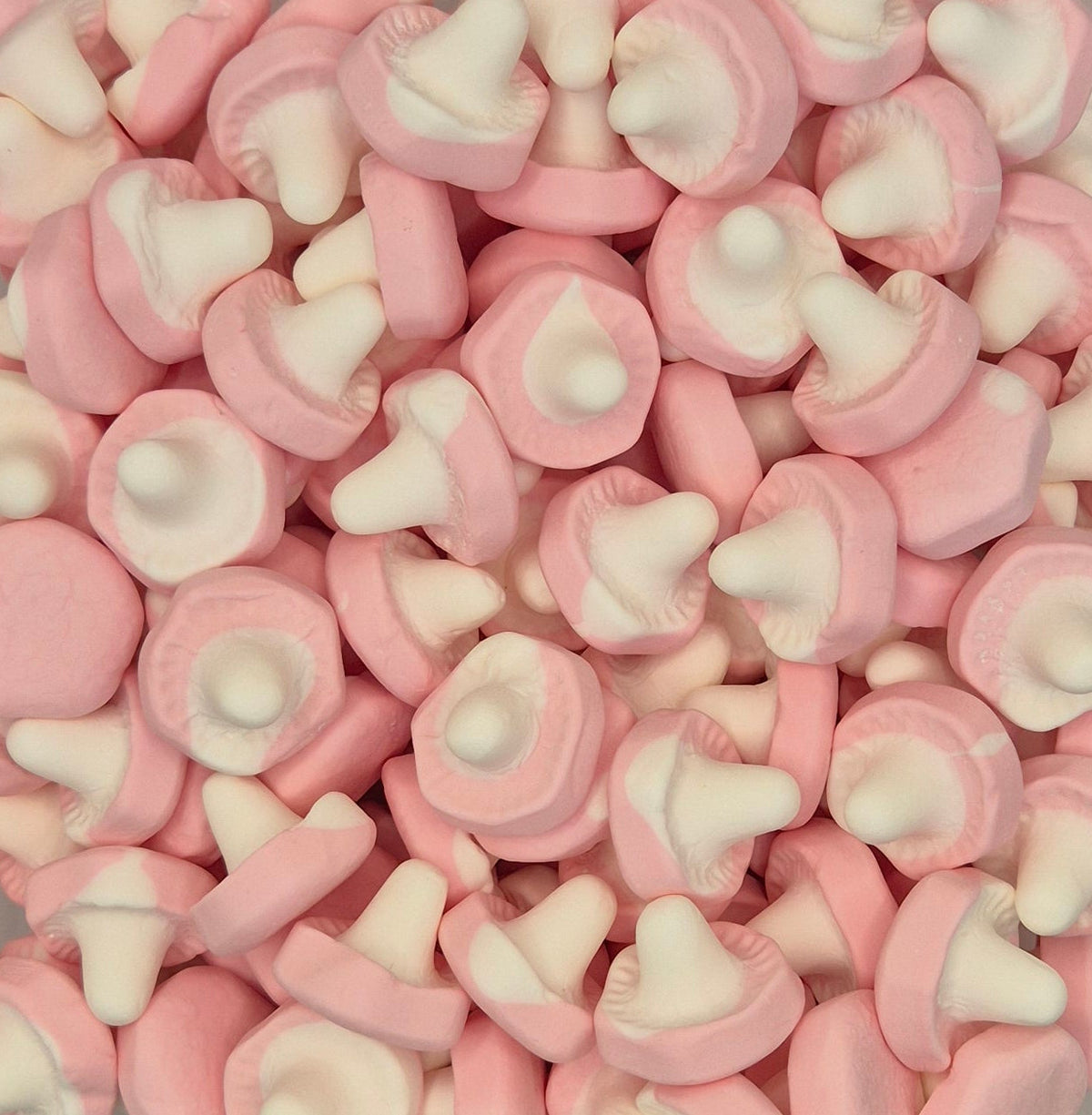 A close-up pile of pink and white mushroom-shaped candies or gummy sweets filling the frame.