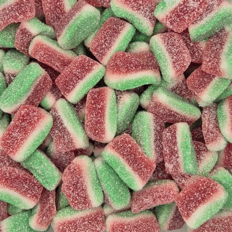 A clear plastic clamshell container filled with sugar-coated gummy candies shaped like watermelons, showing pink-red rinds and green flesh, photographed from above on a light gray background.