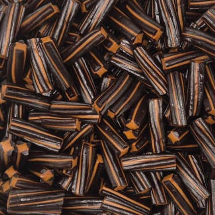 A clear plastic square container filled with many small dark brown and black striped sticks or strips, photographed from above on a plain white surface.