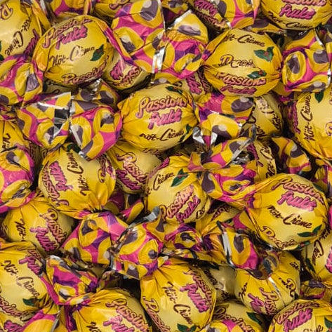 A clear plastic container filled with individually wrapped yellow chocolate eggs, photographed from above on a plain light background.