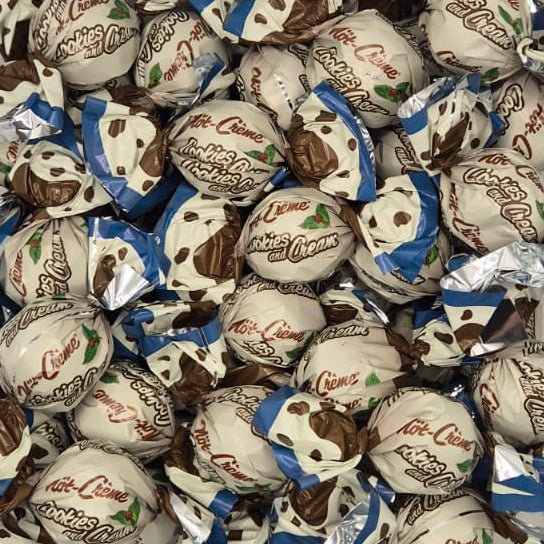 A clear plastic container filled with wrapped chocolate candies, photographed from above on a white surface.
