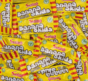 A pile of Swizzels Banana Skids candy bars on a white background.