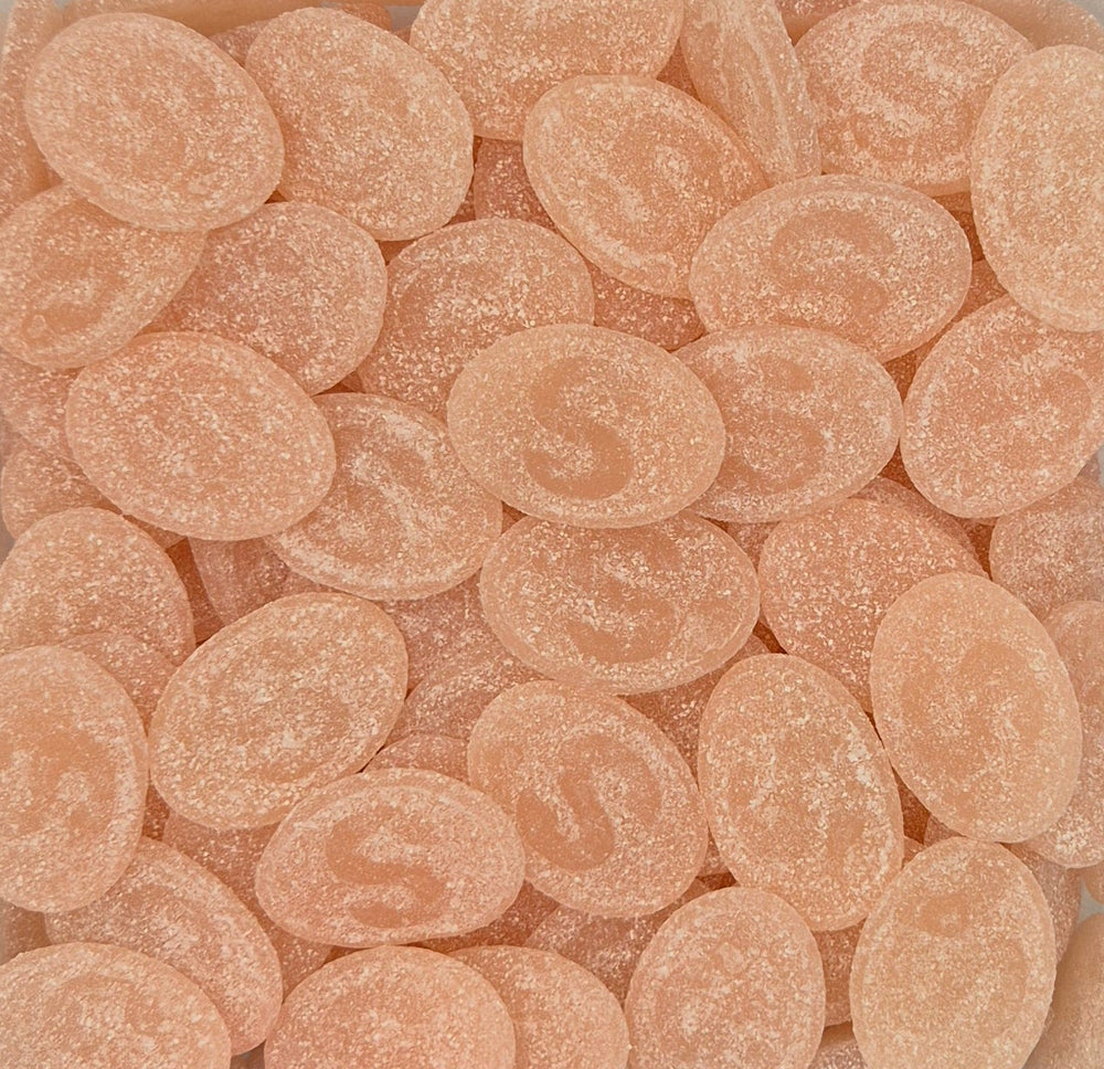 A close-up pile of peach-colored, oval-shaped sugar-coated candies with embossed letter 'S' designs. The famous S-Märke Swedish Candy