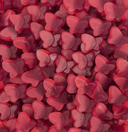 A dense pile of small, glossy, heart-shaped pink candies or gummies filling the entire frame.