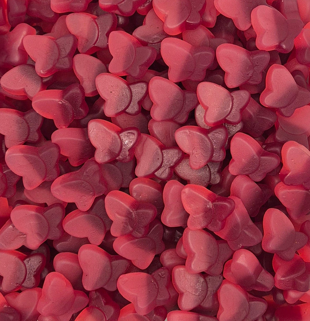 A dense pile of small, glossy, heart-shaped pink candies or gummies filling the entire frame.