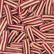 A close-up pile of red and white striped candy sticks, likely peppermint candy, filling the frame.