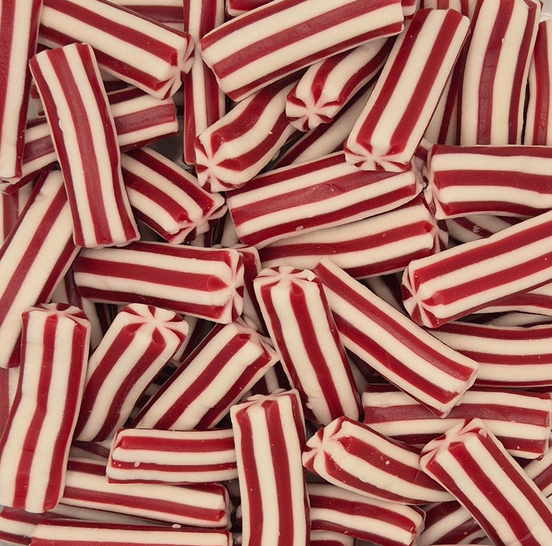 A close-up pile of red and white striped candy sticks, likely peppermint candy, filling the frame.