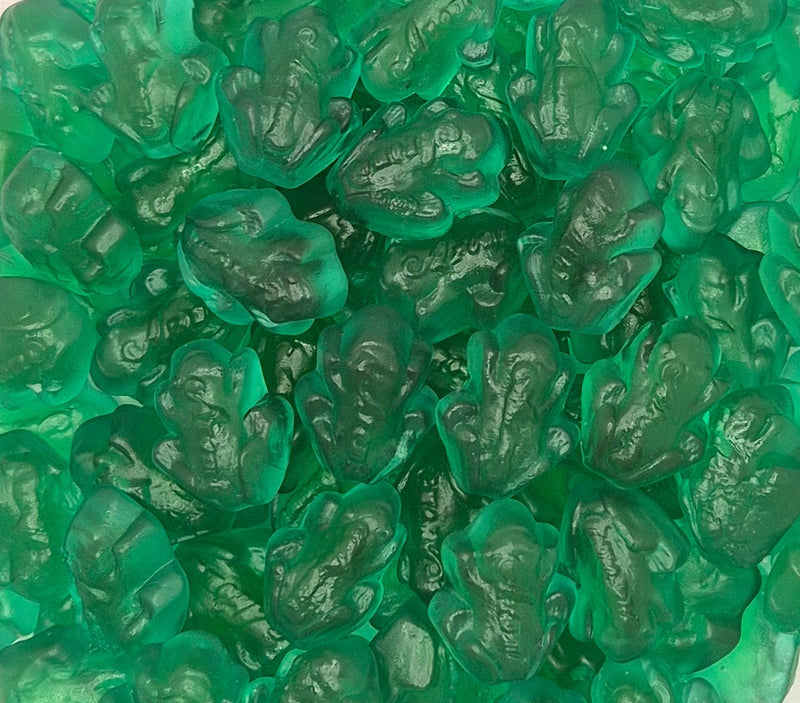 A close-up pile of translucent green gummy candies shaped like frogs, filling the entire frame.