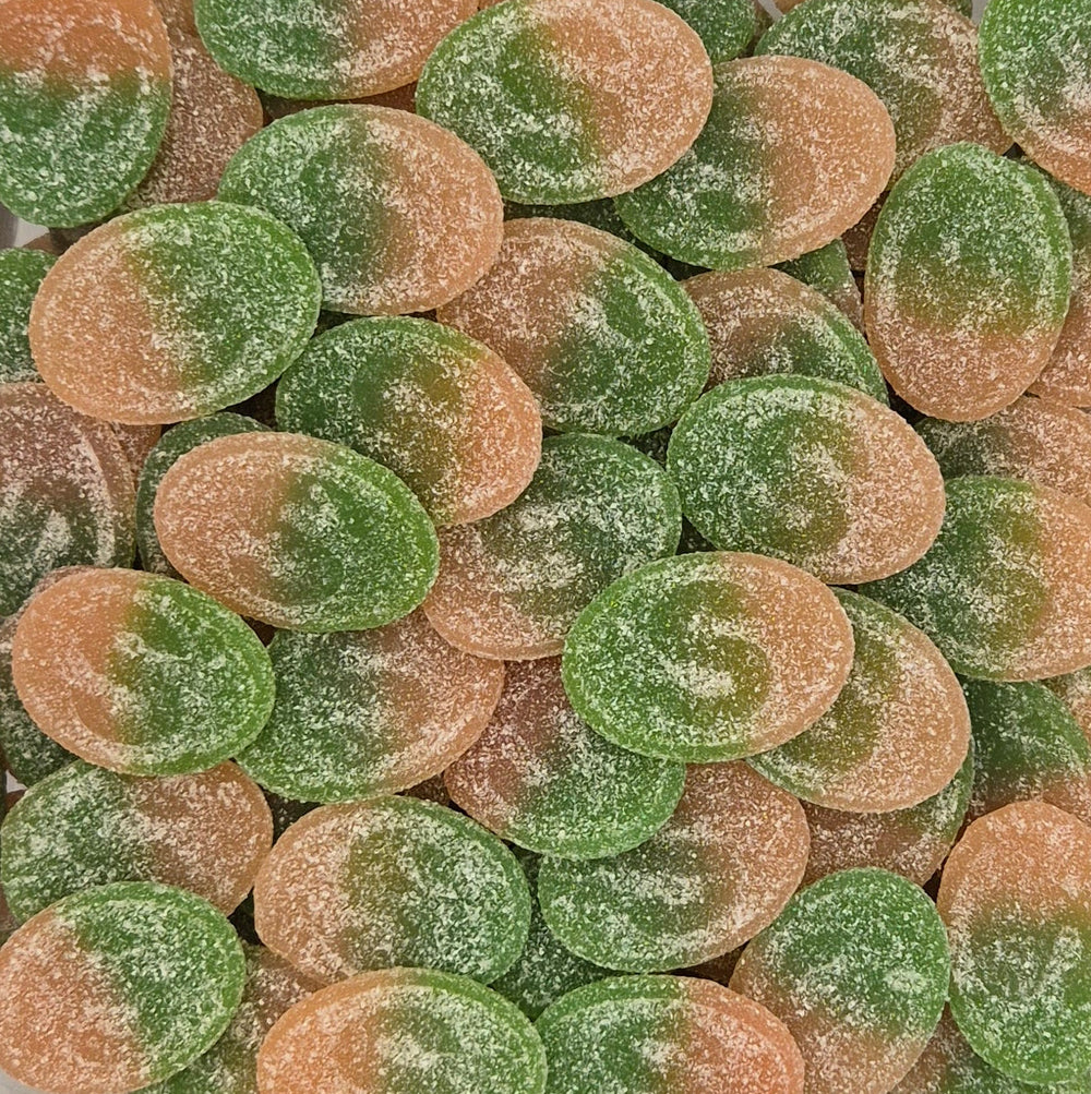 A close-up pile of oval sugar-coated candies in alternating green and peach-orange shades.