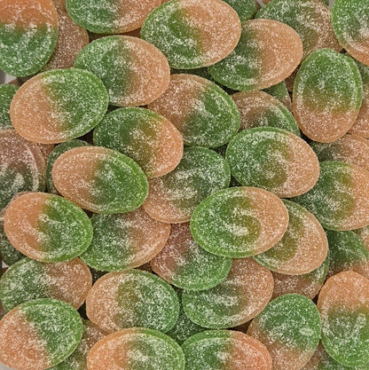 A close-up pile of oval sugar-coated candies in alternating green and peach-orange shades.