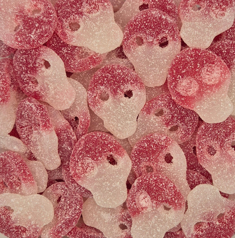 A close-up pile of sugar-dusted skull-shaped candies in red and translucent white.