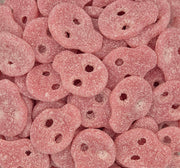 A close-up pile of pink, sugar-coated, irregularly shaped candy pieces with small cutouts, filling the entire frame.