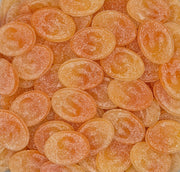 A close-up pile of oval orange candies with a frosted sugar coating and embossed lettering.
