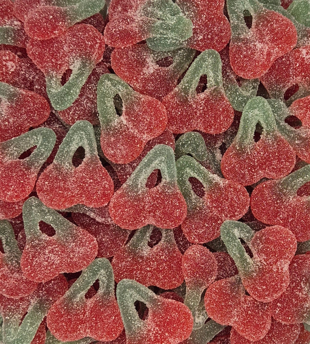 A close-up pile of cherry-shaped sour gummy candies coated in white sugar powder, showing alternating red and green halves.