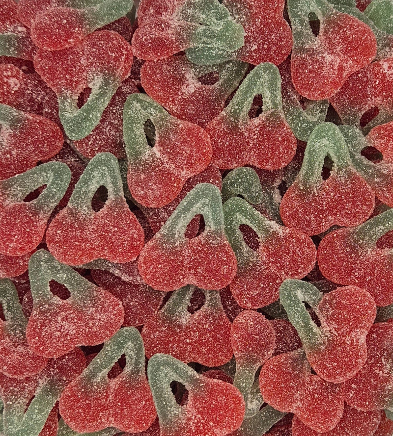 A close-up pile of cherry-shaped sour gummy candies coated in white sugar powder, showing alternating red and green halves.