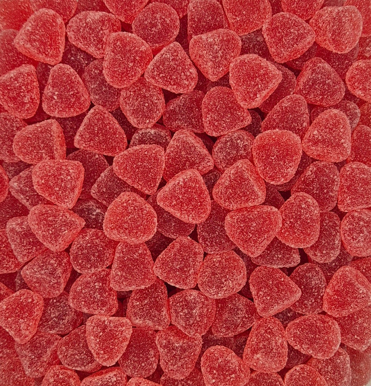 A close-up, top-down view of many small, heart-shaped red gummy candies with a frosted sugar coating, filling the entire frame.