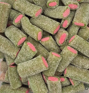 A close-up pile of green cylindrical candy pieces coated with sugar, each showing a pink center.