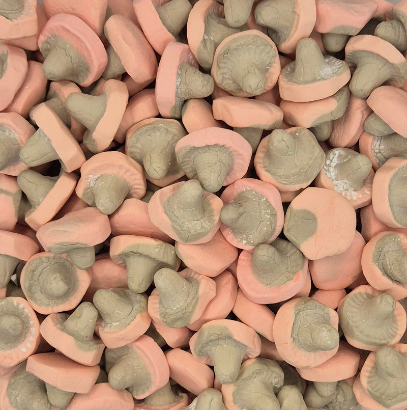 A dense pile of mushroom-shaped candies or gummies, showing both pink caps and pale grayish-brown stems.