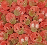 A close-up pile of round, sugar-coated gummy candies shaped like small skulls, showing a mix of red and green tones with white highlights.